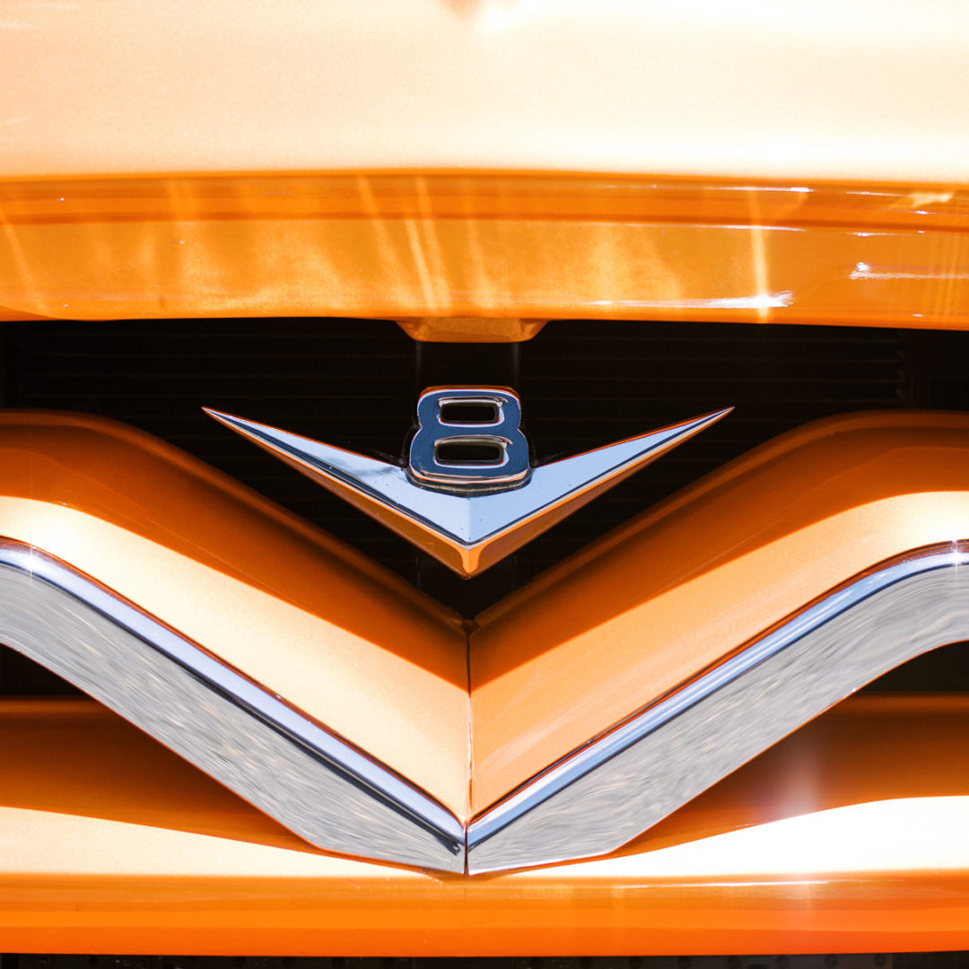 A close up of the front end of an orange car.