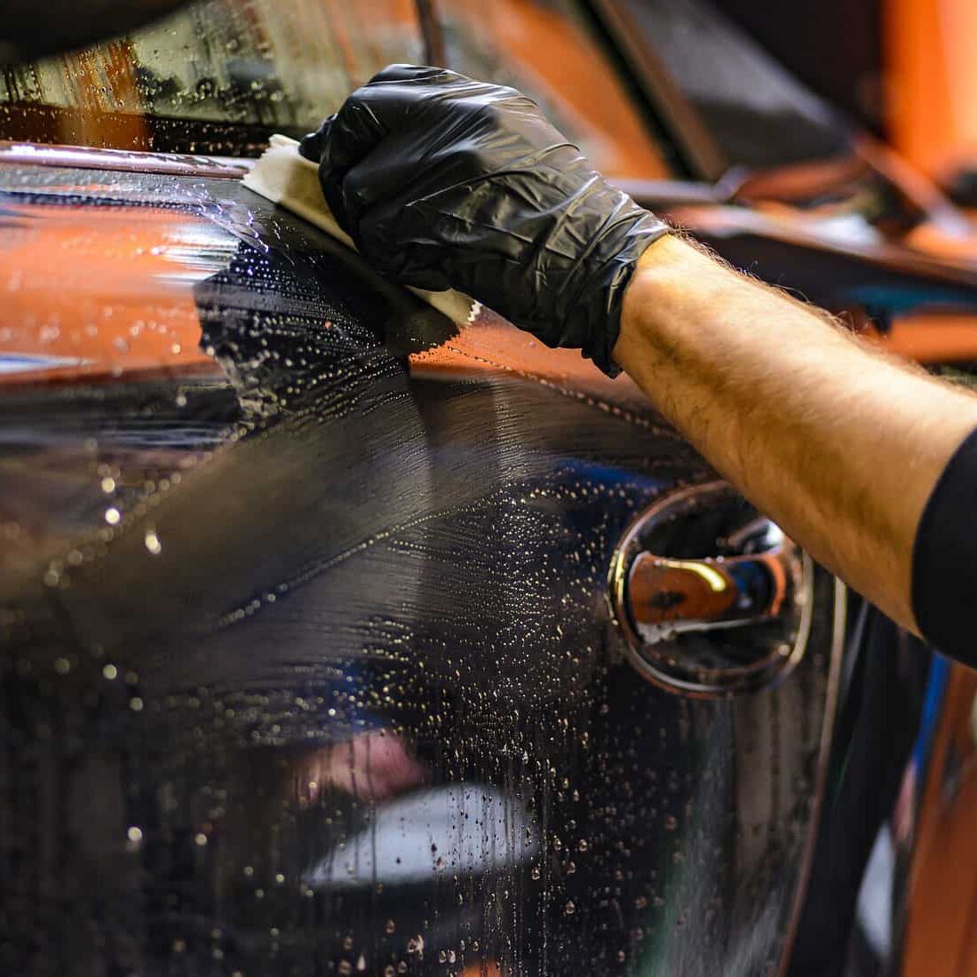 A person wearing gloves and cleaning the car